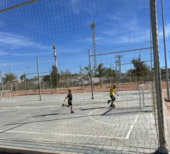 Poisid jalgapalli mängimas puuris