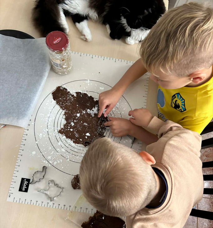 Poisid piparkooke laul voolimas, kass nende kõrval piilumas