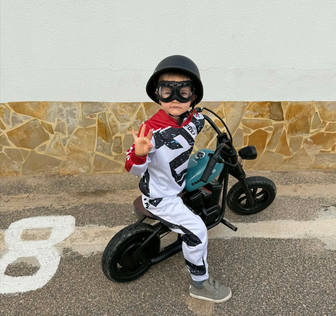 4 aastane poiss istumas chopper stiilis elektrirattal, peas vanaaegne motika kiiver