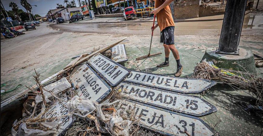 Inimene kokku pühkimas pürgi peale üleujutusi, kus on näha ka linnesilte
